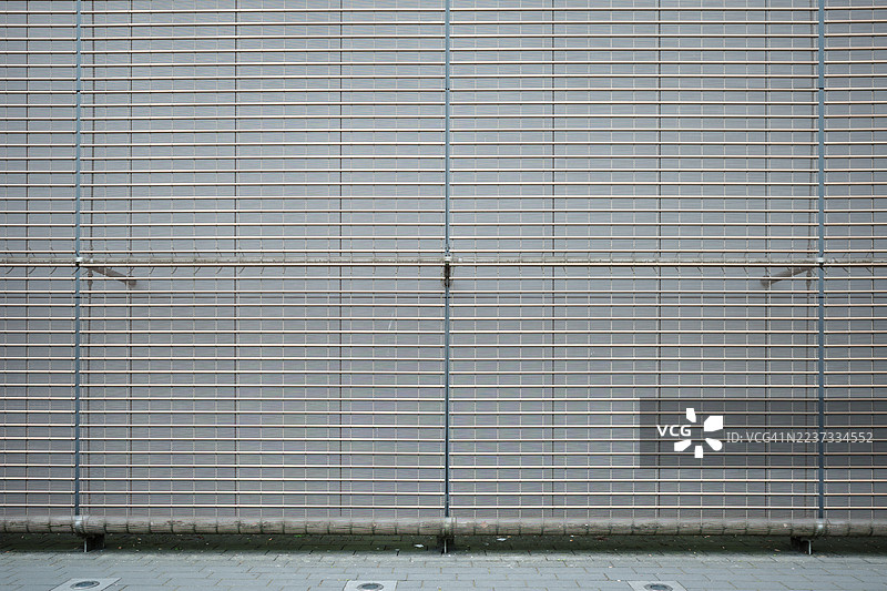 一扇关闭的灰色金属卷帘门，正面、对称的构图，形成了水平线条的几何图案。图片素材