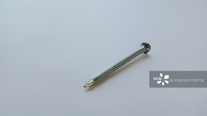 单个镀锌钢钉，孤立在平面上，是建筑、翻新和工业使用的基本硬件工具图片素材