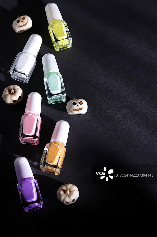 深色背景上色彩缤纷的指甲油瓶和万圣节南瓜装饰图片素材