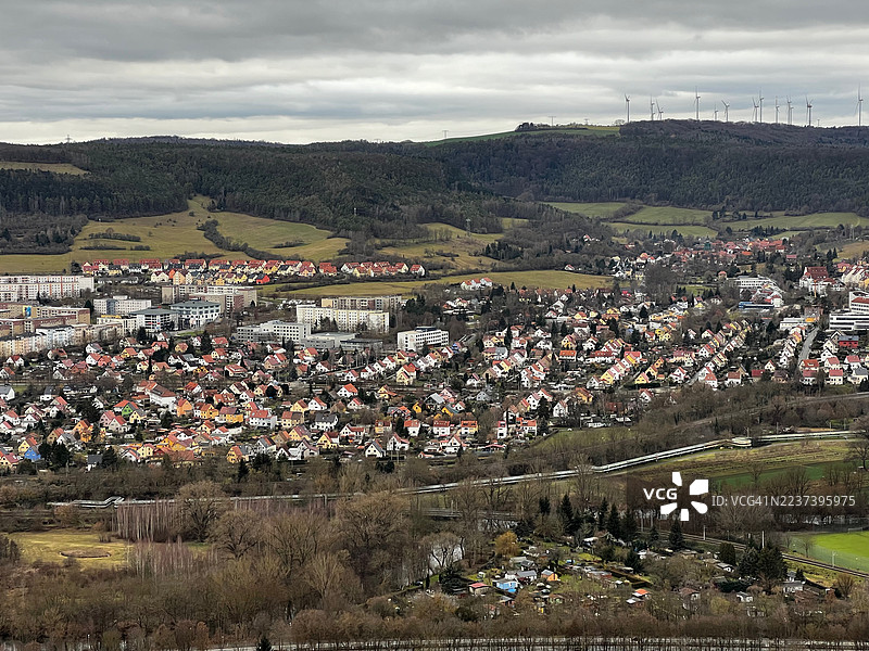 德国耶拿，多云天空下山坡上的城镇景观，住宅房屋和风力涡轮机的高角度视图图片素材