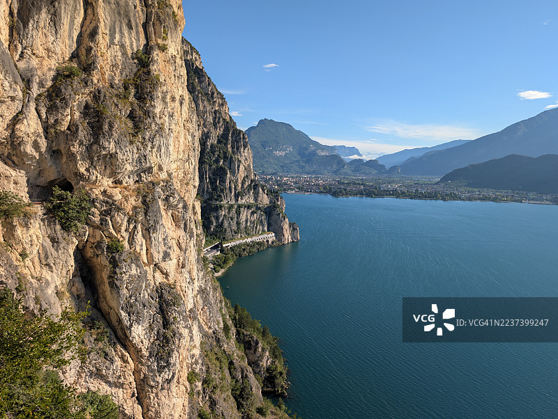 意大利阿尔科，风光明媚的公路蜿蜒于悬崖峭壁之上，湛蓝的天空下，宁静的湖泊被高耸的山峦环绕，构成一幅全景画卷，阿尔卡普兰尼特图片素材