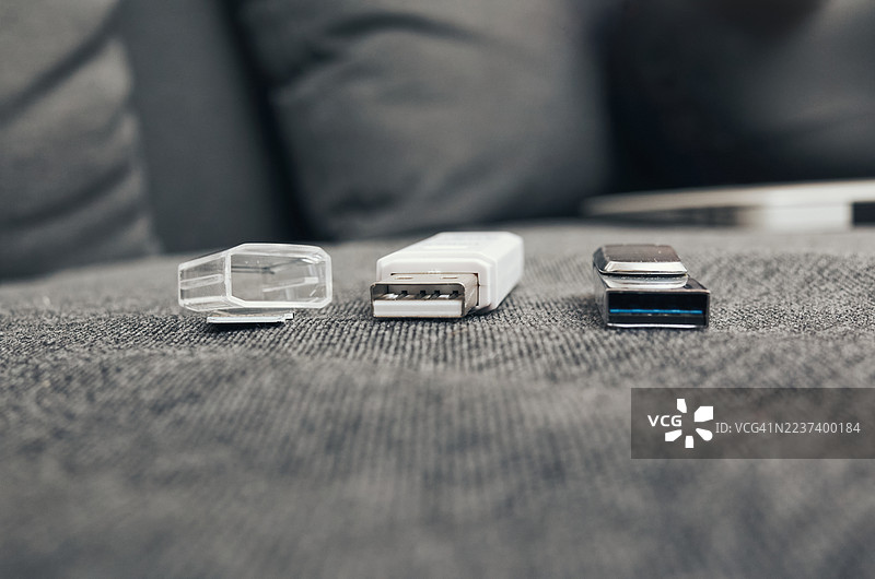 灰色布料表面上三个USB闪存驱动器的特写，强调数据存储和技术图片素材