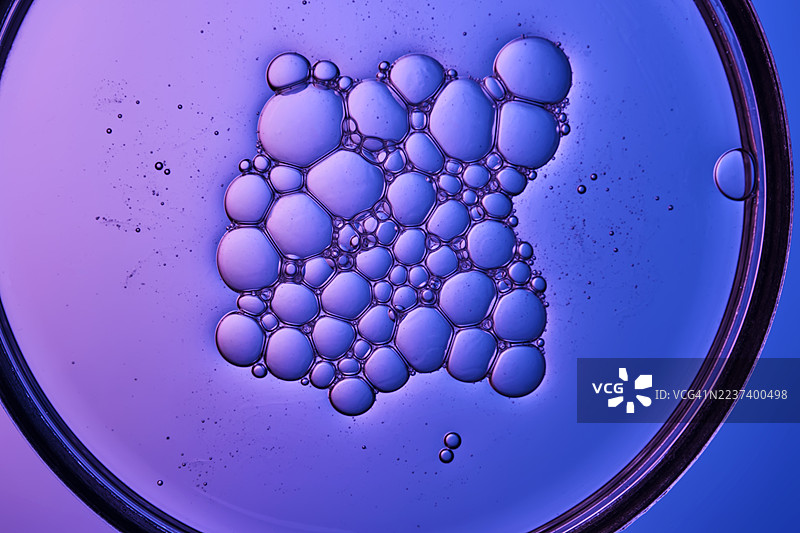 水中有充满活力的紫色和蓝色气泡的特写，在圆形框架内形成抽象图案图片素材