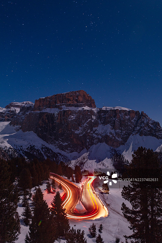 星空下，车灯轨迹勾勒出蜿蜒的山路长曝光影像图片素材