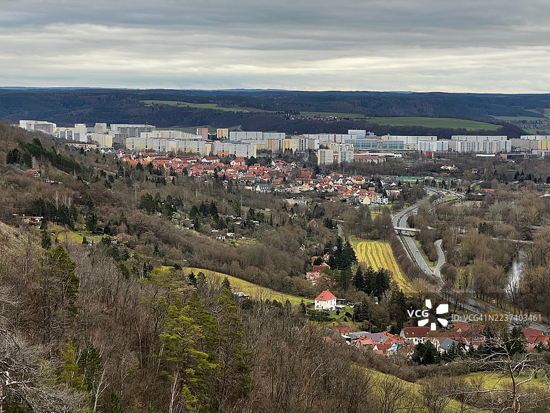 从高处俯瞰耶拿山谷城镇景观，包括住宅楼、道路和山丘，天空阴沉，地点：德国耶拿图片素材