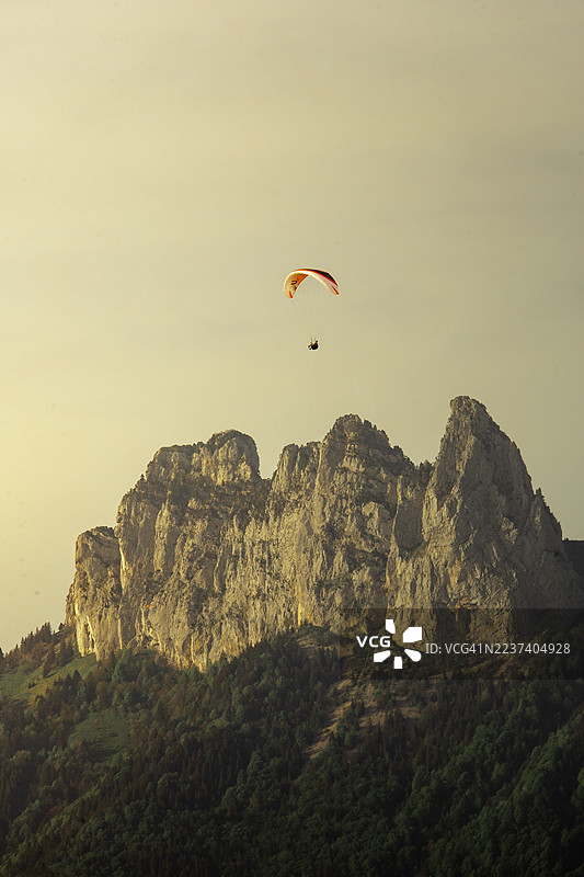 法国安纳西，动力伞在广阔天空下翱翔于雄伟的山脉和森林之上图片素材