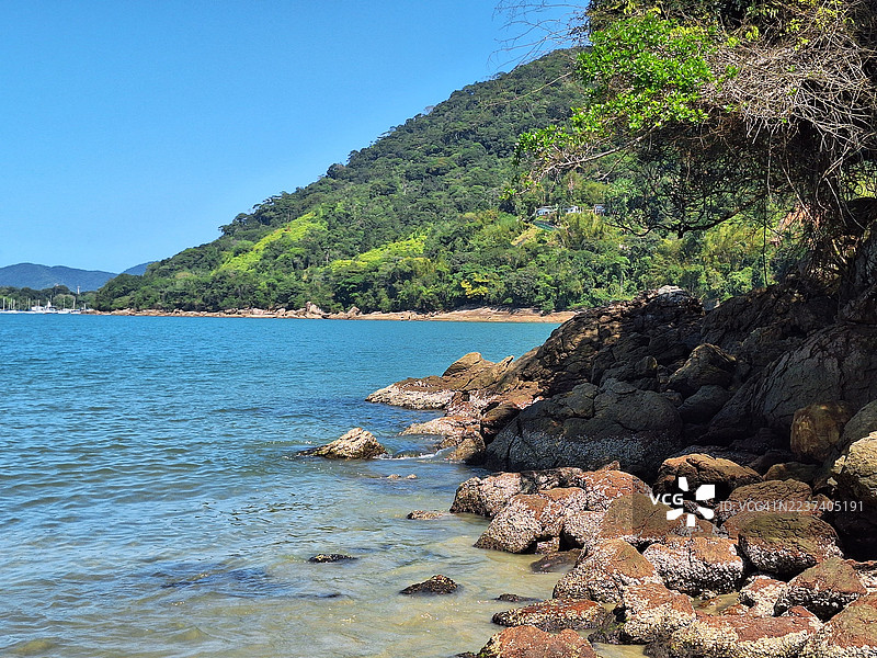 宁静的海景，蔚蓝的天空，郁郁葱葱的绿山和岩石海岸图片素材