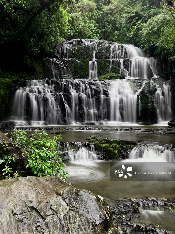 新西兰卡特林斯山脉，雄伟的多层瀑布倾泻而下，穿过郁郁葱葱的绿色森林，长曝光下的水流展现着大自然的美丽。图片素材