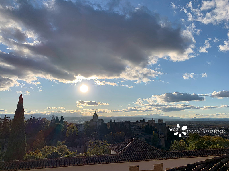 夕阳下的格拉纳达，通用花园，古老建筑，繁茂的树木，云层中射出的阳光，戏剧性的天空，高角度视图，西班牙，历史城镇景观图片素材