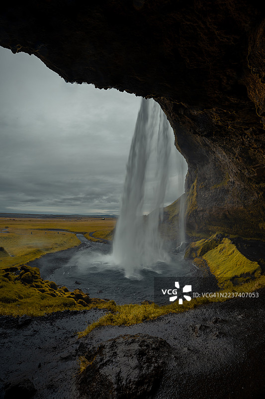 冰岛塞里雅兰瀑布的戏剧性景观，从洞穴内看向外面，头顶是阴沉的天空，冰岛图片素材
