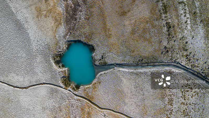 航拍图：生机勃勃的绿松石色盐湖，周围环绕着干裂的土地，展现出独特的自然风光，位于土耳其布尔杜尔（Burdur）。图片素材