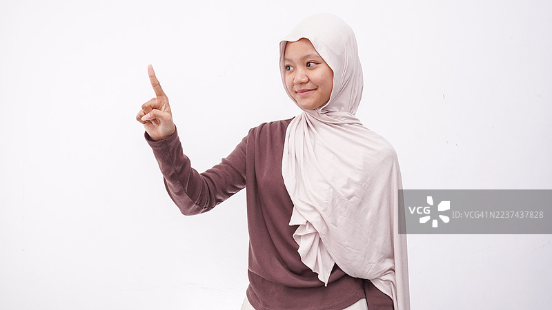 戴头巾的女孩自信地向前伸出食指，象征着方向、指导或领导力，背景为白色。图片素材