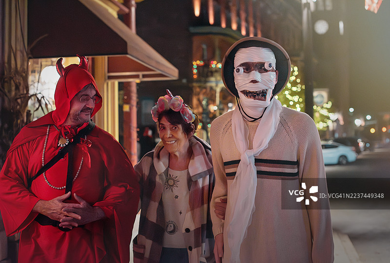 穿着戏服的两名男性和一位老年女性在宾夕法尼亚州的吉姆·索普街上散步。图片素材