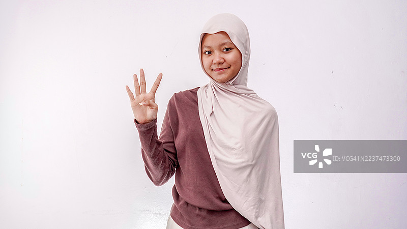 快乐的戴头巾女孩用手指数数。孤立在白色背景上。图片素材
