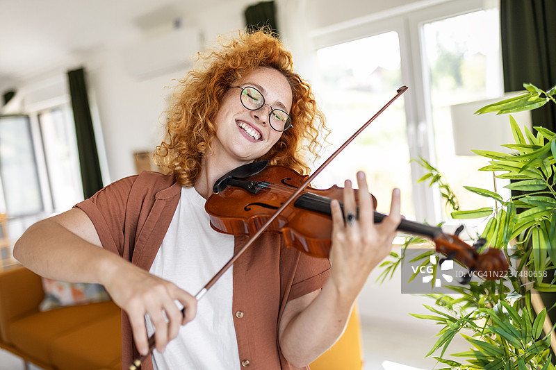 室内享受音乐的女性在拉小提琴图片素材