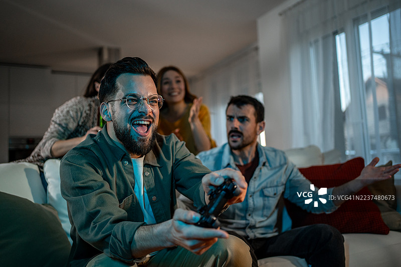 朋友们在客厅里一起玩视频游戏并进行比赛图片素材