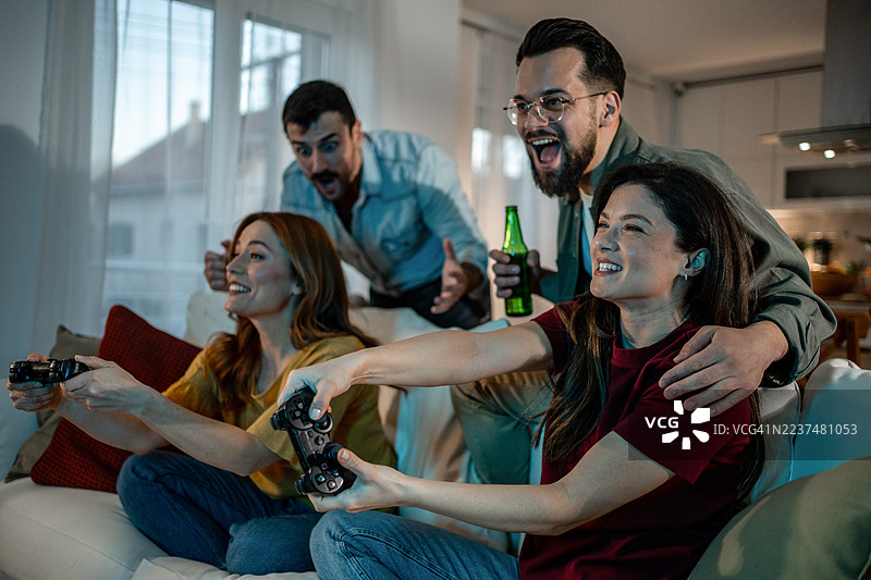 朋友们在家里玩电子游戏，享受快乐时光图片素材