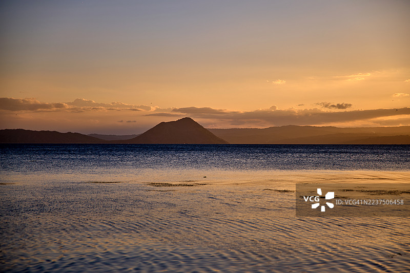 塔尔湖上宁静的日落映照在轻柔的涟漪上。图片素材