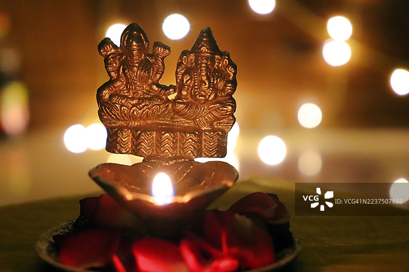 金色的点亮的拉克希米女神、甘尼什神青铜雕像、油灯/玫瑰花瓣/串灯//快乐的排灯节/深瓦利节/丹特拉斯节图片素材