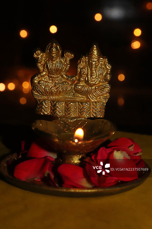 金色的点亮的拉克希米女神、甘尼许神的黄铜雕像、油灯/玫瑰花瓣/串灯//快乐的排灯节/深瓦利节/丹特拉斯节图片素材