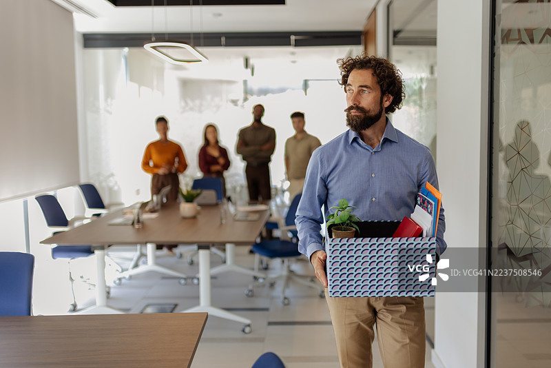 被解雇的员工提着装有个人物品的箱子走出办公室图片素材