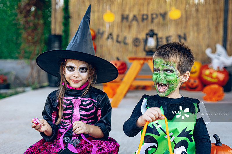 快乐的孩子们一起庆祝万圣节，手里拿着糖果桶图片素材