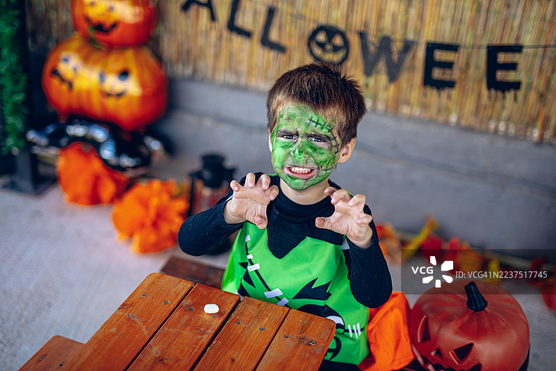 微笑的孩子在万圣节庆祝活动中做出恐怖的表情图片素材