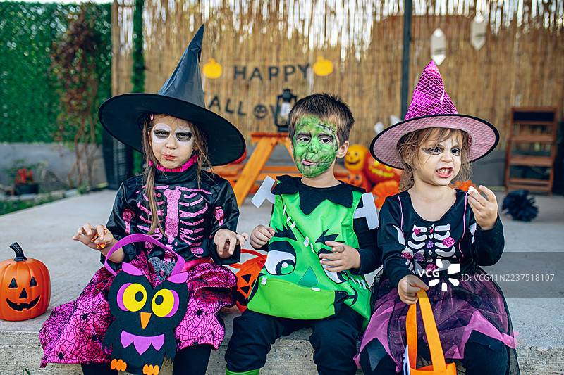 一群孩子穿着 costumes 进行万圣节讨糖活动图片素材