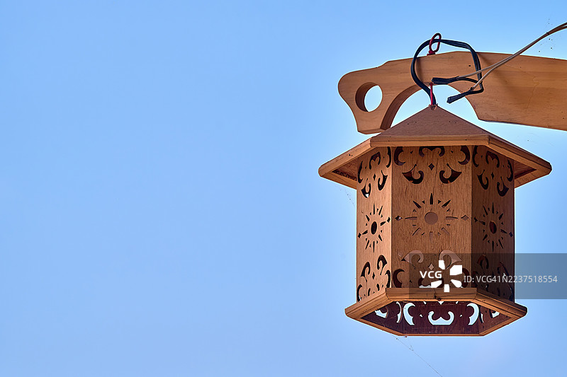 一个六角形的木制灯笼，精美雕刻着花卉和星形图案。图片素材