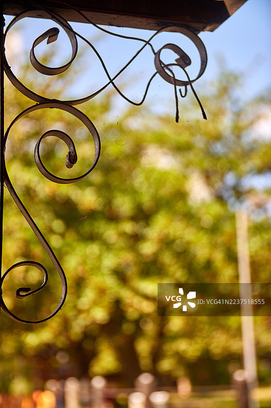 一个特写镜头，展示了一个深色、华丽的锻铁装饰支架，带有复杂的卷曲和旋涡。图片素材