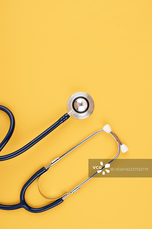 明亮的黄色背景下的听诊器。图片素材