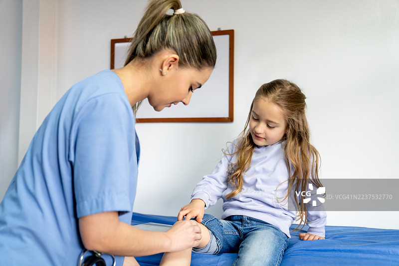 校医正在为一名女孩处理腿部伤口图片素材