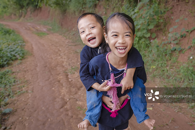 老挝女孩在老挝北部的一个村庄里背着她的小弟弟图片素材