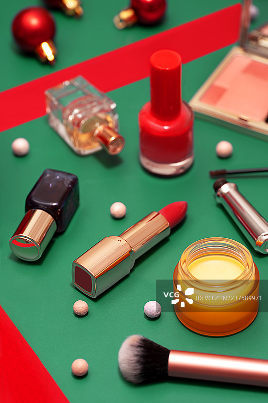 冬季假期拼贴：圣诞快乐，新年快乐和黑色星期五，由美容化妆品、红色礼品盒、丝带和圣诞装饰品在绿色青色背景上排列而成。图片素材