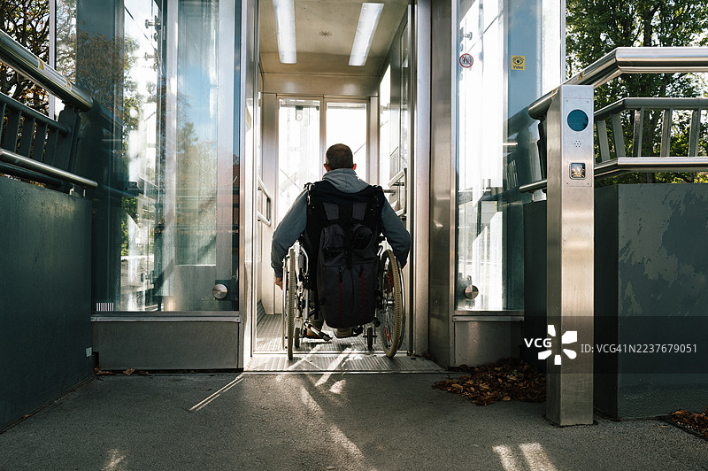 男子使用轮椅升降机进入公共交通工具图片素材