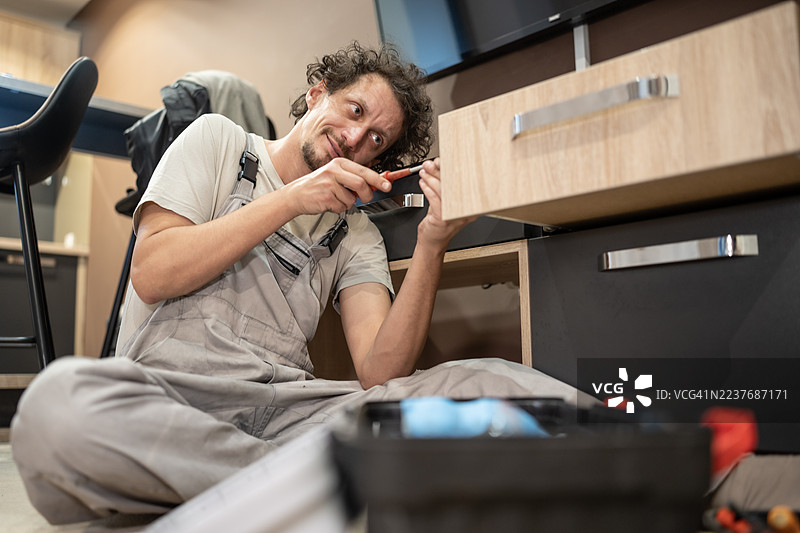 勤劳的工匠在厨房台面下安装橱柜抽屉，手持工具图片素材