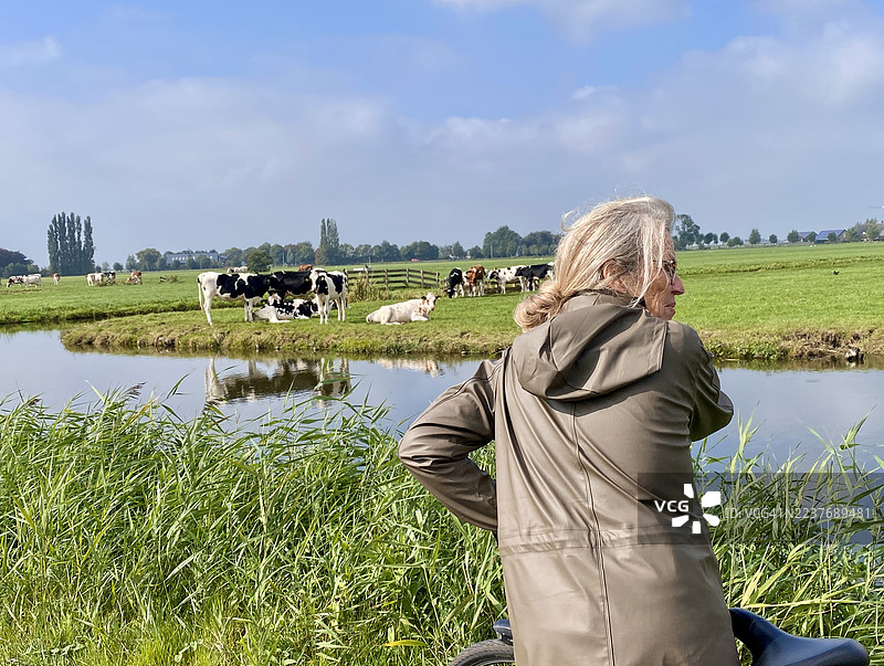 一位年长女士在荷兰圩田享受自行车周末。图片素材