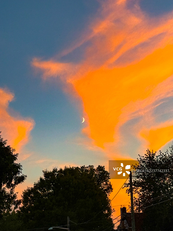 在黄昏时分，Teaneck的蓝橙色天空中可见细长的月牙弯曲。图片素材