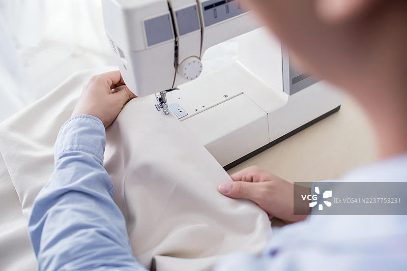 一个人用缝纫机缝制布料图片素材
