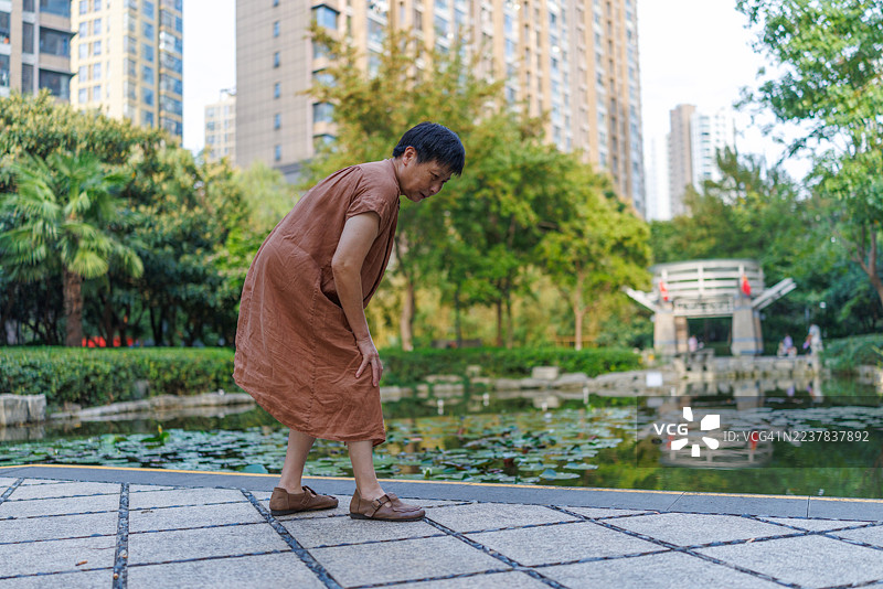 一位60多岁的中国女性在户外，膝盖感到疼痛。图片素材