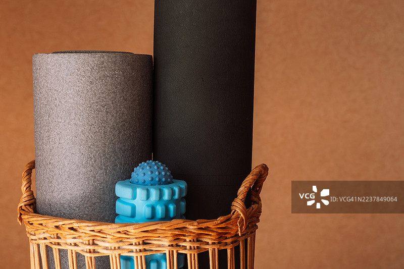 编织篮子里的卷垫和泡沫滚筒，家庭健身角落。图片素材