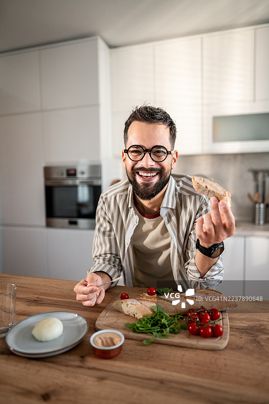 快乐的男人享用新鲜法棍和马苏里拉奶酪的健康早餐图片素材