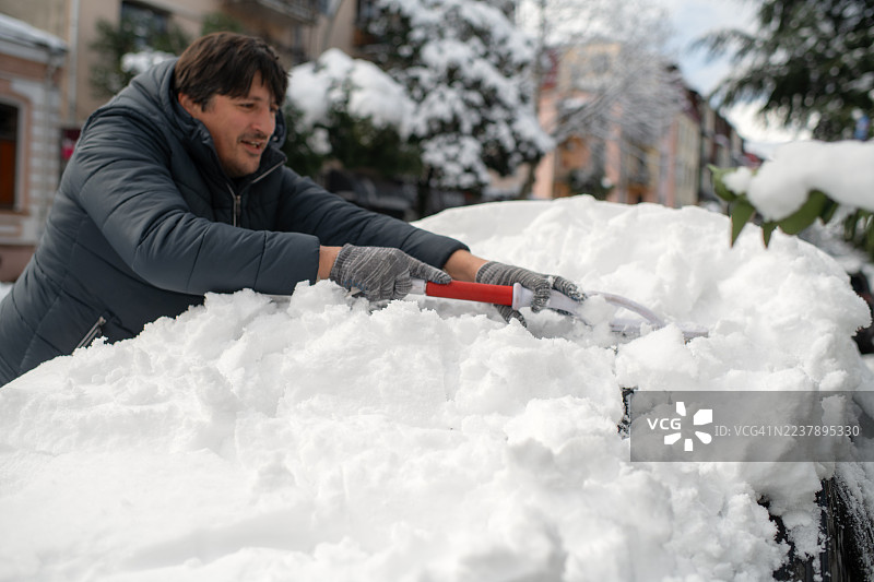 大雪过后，一名男子正在清洗他的汽车。图片素材