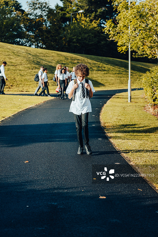 英国纽卡斯尔泰恩河畔肯顿镇一所高中校园内，学生们在阳光明媚的早晨沿着小径行走图片素材