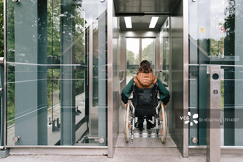 女性使用轮椅升降机进入公共交通工具图片素材