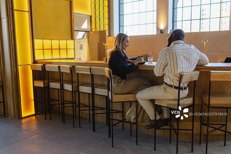 两位同事在一家时尚餐厅享用休闲午餐，餐厅灯光温暖，内饰现代。图片素材
