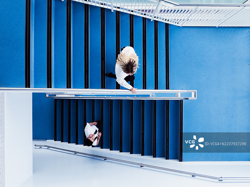 无人机视角拍摄，一名十几岁的女孩和一名十几岁的男孩站在纽卡斯尔大学蓝色楼梯的不同层上，互相看着对方，地点位于英格兰，英国纽卡斯尔。图片素材