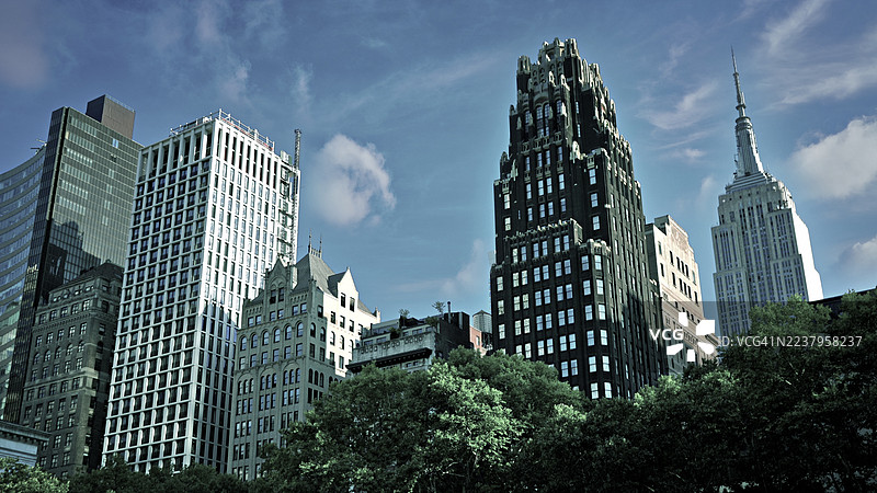 宏伟的纽约摩天大楼耸立在郁郁葱葱的绿树之上，帝国大厦高耸入云，尽收眼底。美国纽约州纽约市。图片素材