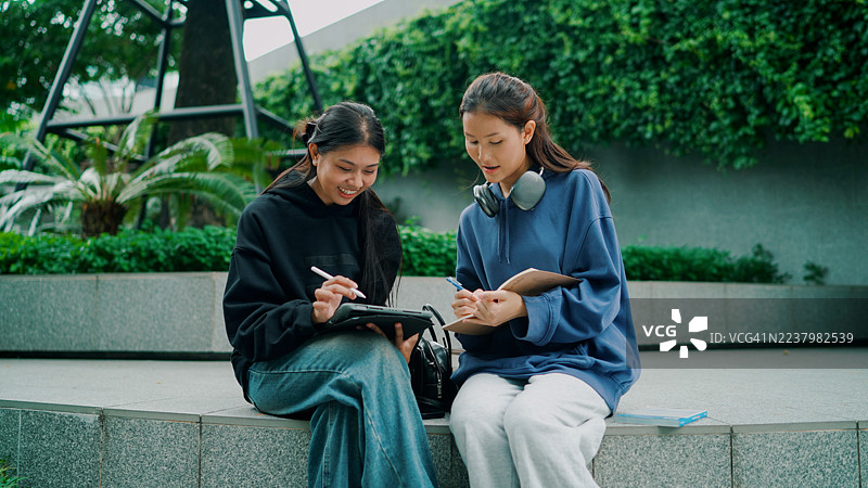 年轻的亚洲女性在大学课后与朋友分享笔记。图片素材