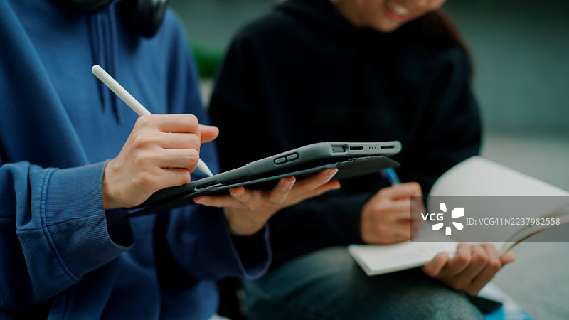 年轻的亚洲大学生在下课后互相分享笔记。图片素材